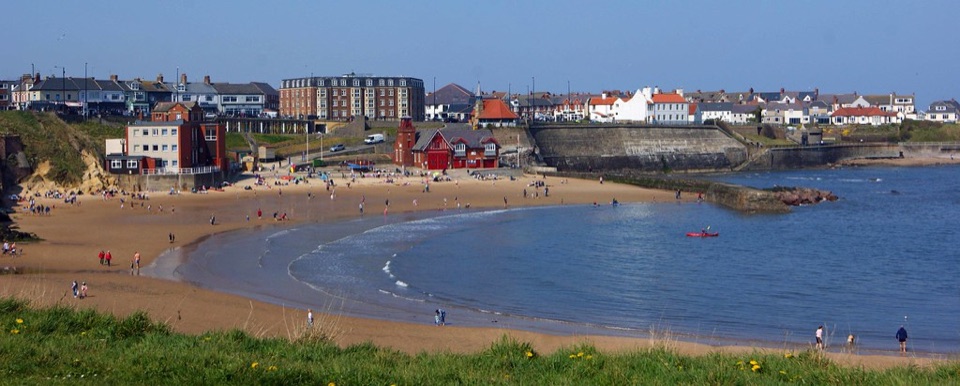 The bay at Cullercoats with houses along the seafront above the beach