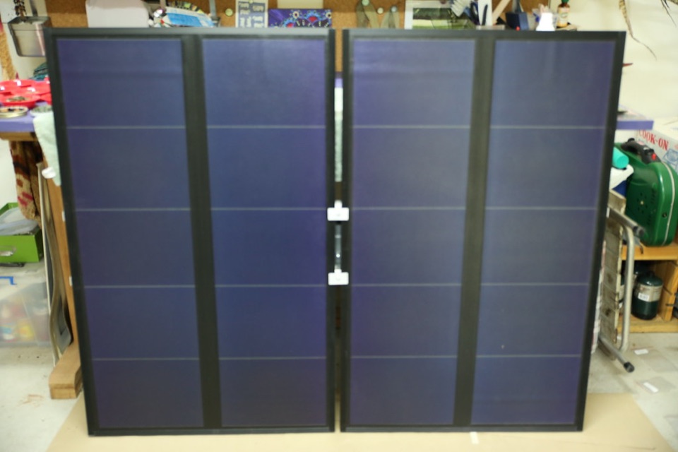 Four solar panels on a free standing frame on open ground in a garden